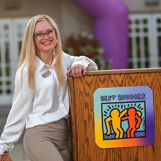 A female Buddy Ambassador standing at a podium delivering a speech.