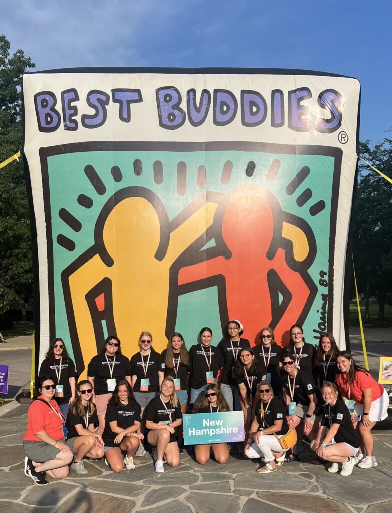 Best Buddies participants from New Hampshire and Vermont posing in front of an inflatable Best Buddies sign. The sign is a large Best Buddies Logo reading “Best Buddies”.