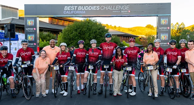 Participants at the starting line of the 21st Best Buddies Challenge: California, presented by Safeway Foundation, posing under the event banner with cyclists and Best Buddies representatives.