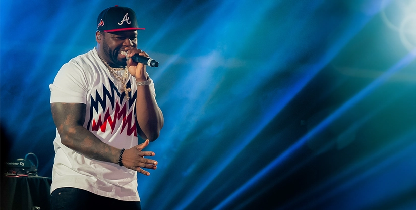 Rapper performing on stage at the Best Buddies Challenge Hyannis Port, wearing a white patterned shirt and Atlanta Braves cap. Event presented by Shaw's, Star Market Foundation, and TJX.