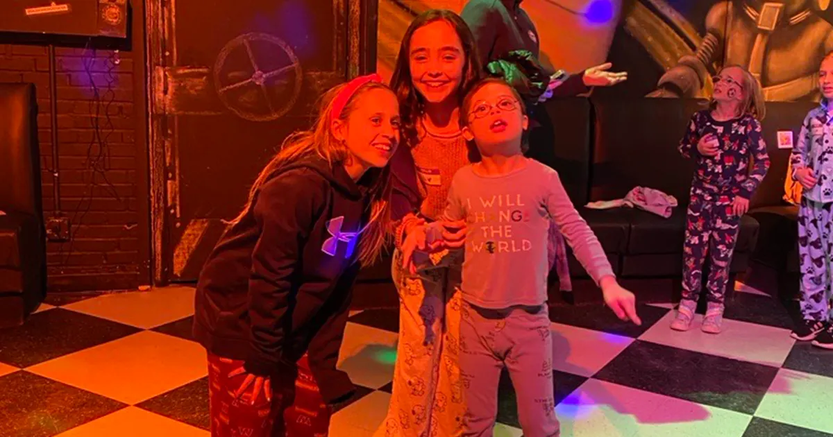 Three elementary school children with and without intellectual and developmental disabilities in their pajamas and smiling for a photos. 